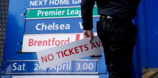 A member of ground staff adjusts a match board ahead of the upcoming Premier League match between Chelsea and Newcastle at Stamford Bridge (AP)
