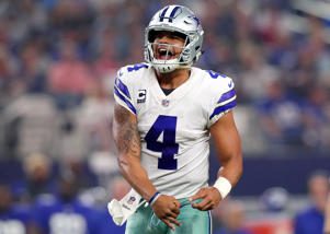 a man standing in front of a crowd: Dak Prescott #4 of the Dallas Cowboys celebrates after throwing a touchdown pass to Jason Witten #82 of the Dallas Cowboys in the second quarter against the New York Giants at AT&T Stadium on September 10, 2017 in Arlington, Texas. Tom Pennington/Getty Images