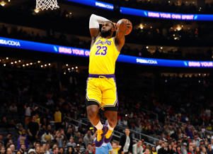 a man standing in front of a crowd of people watching a football game: LeBron James #23 of the Los Angeles Lakers dunks against the Atlanta Hawks in the first half at State Farm Arena on December 15, 2019 in Atlanta, Georgia. NOTE TO USER: User expressly acknowledges and agrees that, by downloading and/or using this photograph, user is consenting to the terms and conditions of the Getty Images License Agreement. Kevin C. Cox/Getty Images