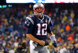 a man holding a baseball bat in front of a crowd: Tom Brady #12 of the New England Patriots cheers as he runs on to the field before the game against the Pittsburgh Steelers at Gillette Stadium on September 10, 2015 in Foxboro, Massachusetts. Jim Rogash/Getty Images