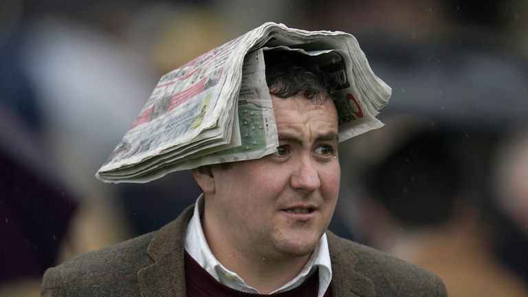 A racer uses a sheet of paper to protect from the rain in Cheltenham