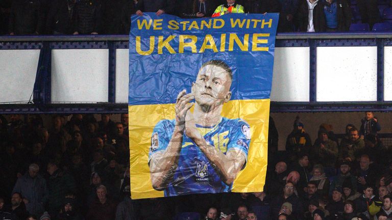 Fans in the stands with a banner reading Everton's Vitaly Mikolenko "We stand with Ukraine"