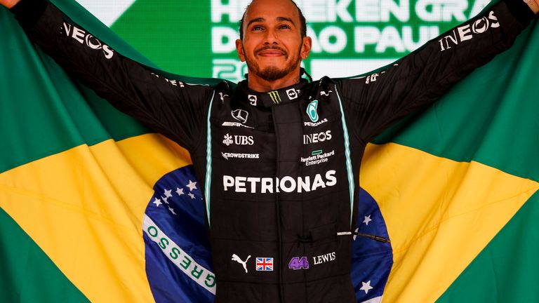     Lewis Hamilton carries the Brazilian flag after winning the Brazilian GP last year