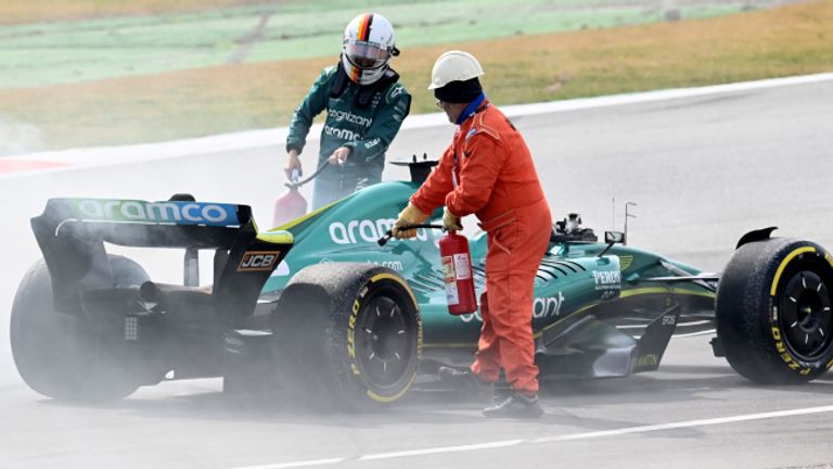 Marshals help Sebastian Vettel after an oil spill on his Aston Martin